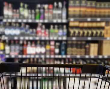 Abstract blurred image of alcohol store with trolley (Selective focused at shopping cart)