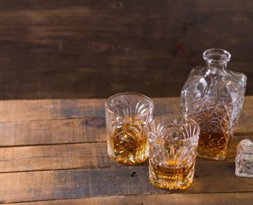 bourbon whiskey in glass on wooden background