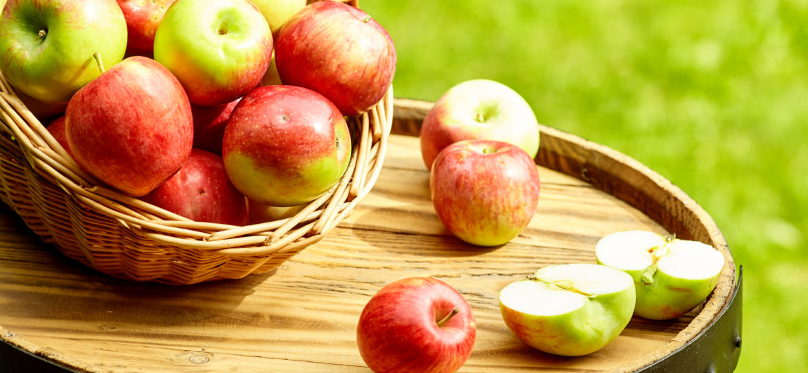 Beautiful apples on garden background on the old barrel