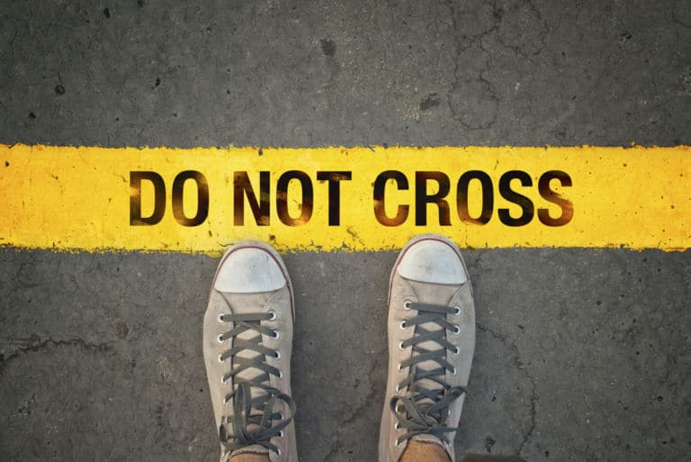 Ein Bild aus der Ego Perspektive auf den Boden, bei dem Jemand mit Schuhen an einer gelben Linie mit der Aufschrift "Do not Cross" steht. Das Titelbild zur Folge 33 – Tsu-Mū Tung