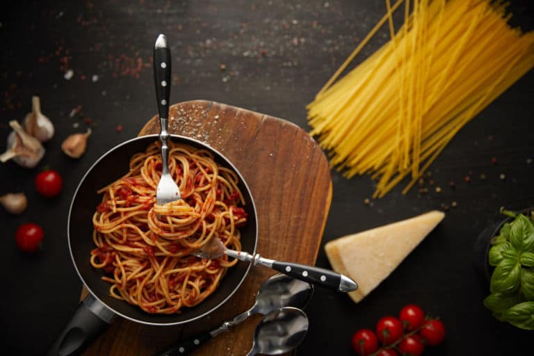 Ein Bild von einer Schale voller Spaghetti mit Besteck die auf einem Tisch voller Zutaten für das Gericht steht. Das Titelbild zur Folge 36 – Zwei Whiskys für ein Halleluja