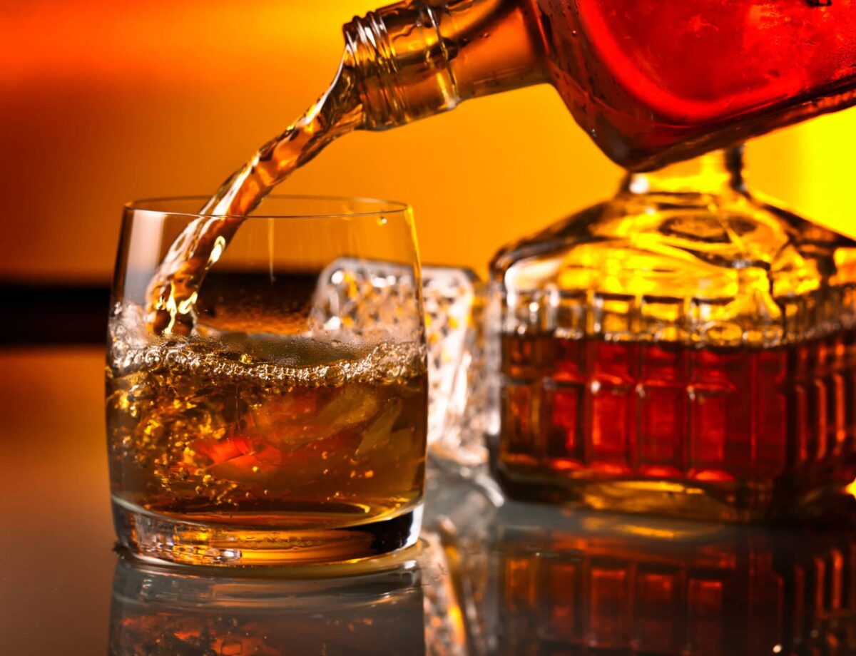 Im Bild wird ein Glas Whisky eingeschenkt als Titelbild zur Folge 43 – Darf es ein bisschen (Tulla-)more sein?