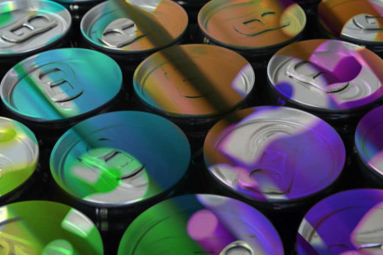 Eine schräge Draufsicht auf mehrere Dosen die durch das Licht, das durch verschiedenfarbige Fenster scheint, beleuchtet werden. Das Titelbild zur Folge 48 – Whisky-Cola-Dosen aus dem Discounter: Can the can?