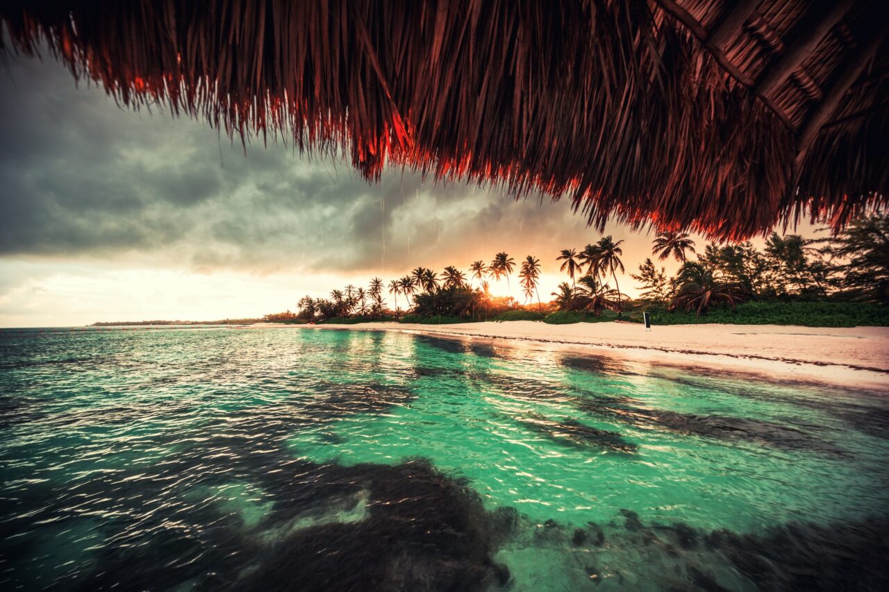 Ein Bild von einem Sonnenuntergang in einer Strandhütte in der Karibik als Titelbild zur Folge 72 – Mit Bahama Mama in den Frühling