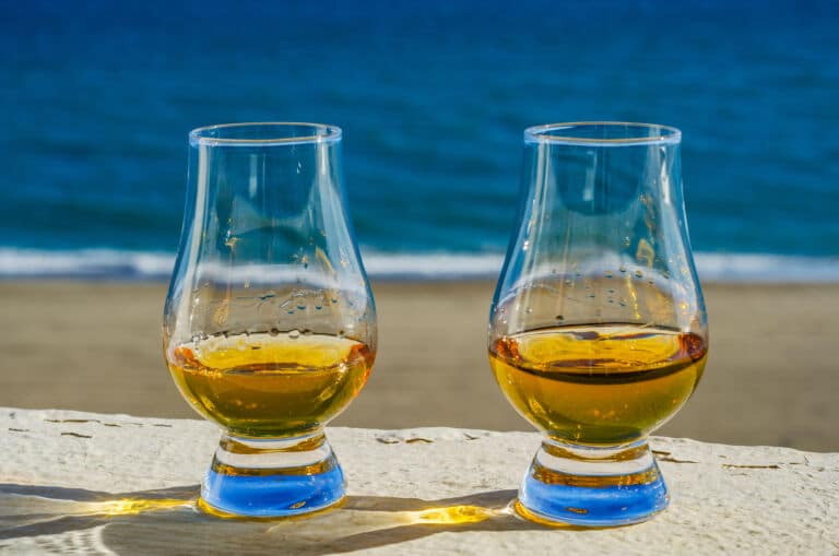 Zwei Glencairn Gläser mit Whisky am Strand als Titelbild zur Folge 87 – Leichter Sommer-Whisky