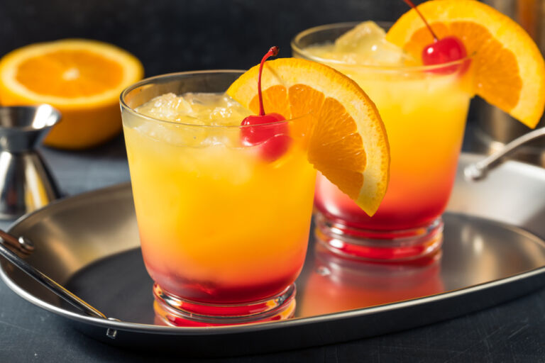 Zwei Cocktails mit Orange , Cocktailkirsche und Eis auf einem Metalltablett. Das Titelbild zur Folge 119 – Jim Beam Sunshine Blend: Ein Sommermärchen?