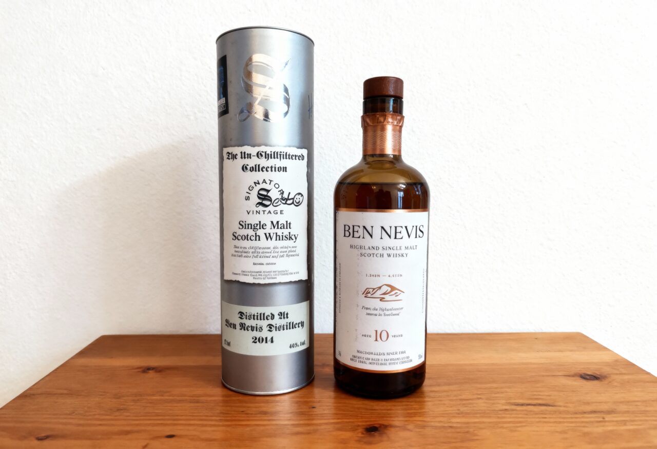 Ben Nevis 10 Jahre Highland Single Malt Whisky-Flasche neben Signatory Vintage „Un-Chillfiltered Collection“ Tube (Ben Nevis 2014) auf einem Holztisch vor heller Wand.