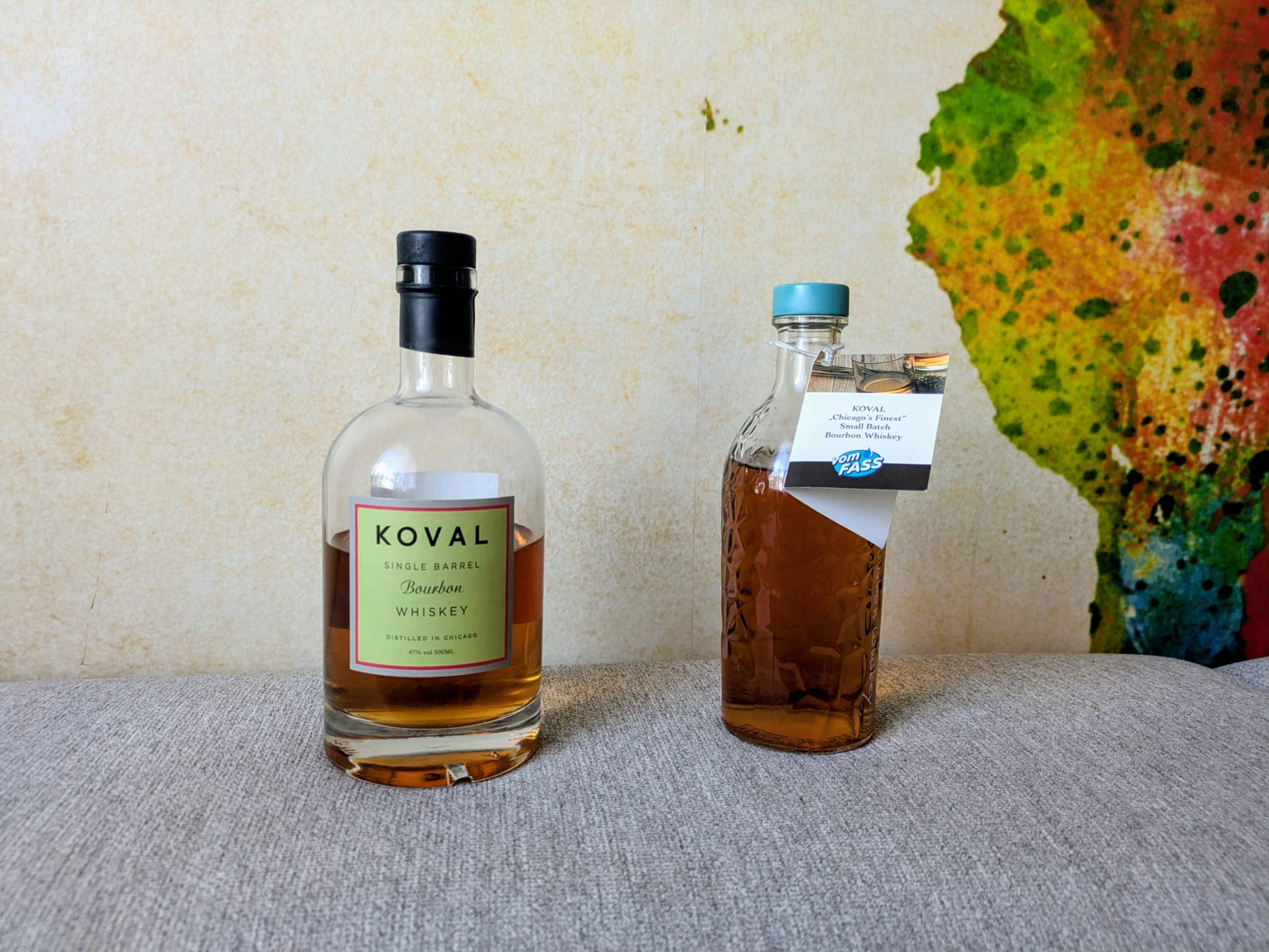 Koval Single Barrel Bourbon Whiskey und Koval Chicago’s Finest Small Batch Bourbon Whiskey stehen nebeneinander auf einem grauen Untergrund.
